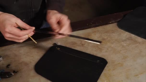 close up shot of mans hands, who draws on a piece of leather line using a ruler - Footage, Video