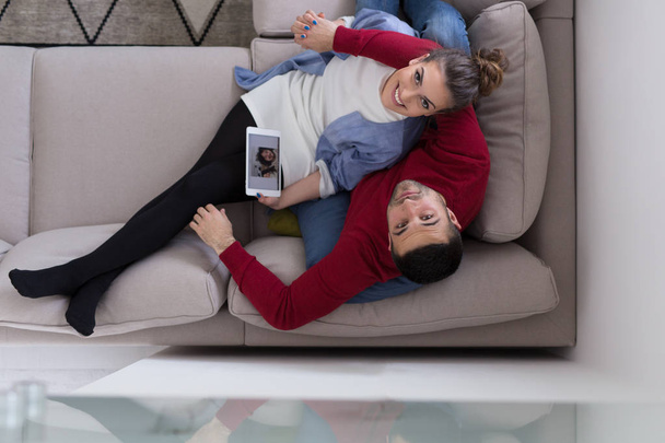 ζευγάρι χαλαρά στο σπίτι με υπολογιστές tablet - Φωτογραφία, εικόνα
