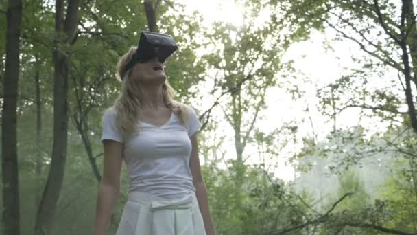 Young woman in the forest uses VR virtual reality glasses and is amazed by nature - Video, Çekim