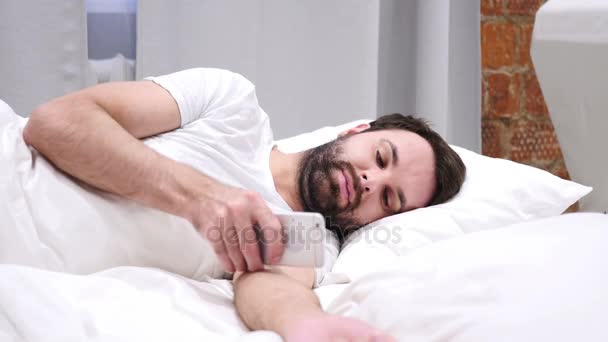 Ο άνθρωπος στο Smartphone, περιήγηση, ηλεκτρονικό ταχυδρομείο και μηνύματα, ξαπλωμένη στο κρεβάτι πλευρά - Πλάνα, βίντεο