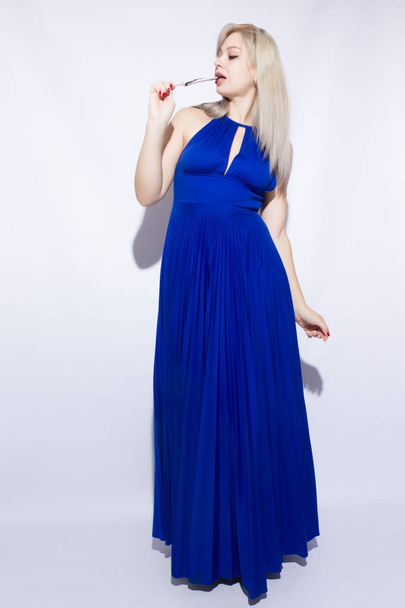Portrait of a beautiful young blond woman with long hair in blue maxi dress. Girl holding a heart shaped cand - Foto, Bild