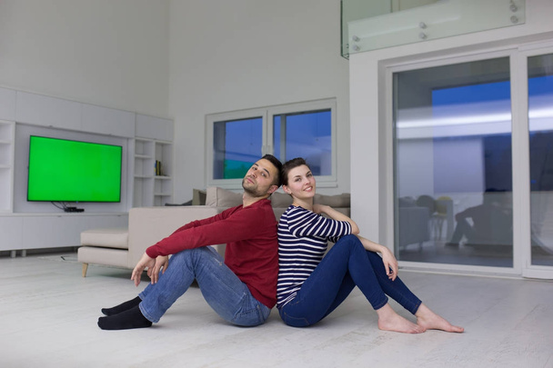 young couple sitting with back to each other on floor - Foto, Bild