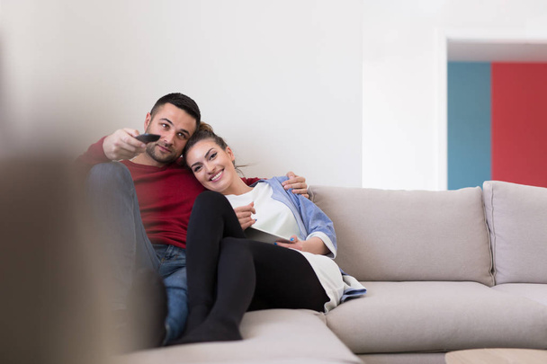 Young couple on the sofa watching television - Фото, изображение