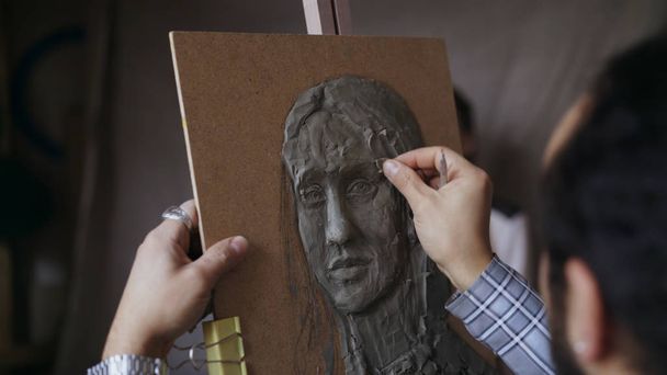 Close-up of Sculptor creating sculpture of humans face on canvas in art studio - Photo, Image