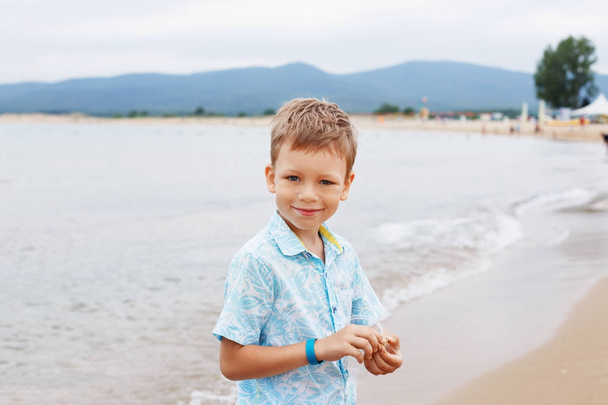 シャツやショート パンツ、ビーチの砂の上に小さな男の子。小さな少年の海 - 写真・画像