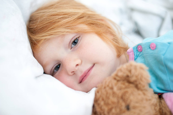 Red-haired girl is sleeping with her pet toy - Fotografie, Obrázek