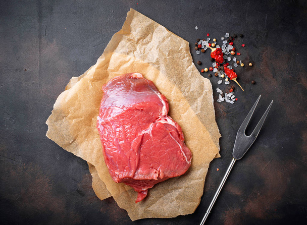 Raw meat steak with spices on rusty background - Photo, Image