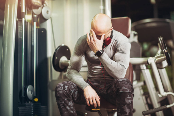 πορτρέτο του ανήσυχος άνθρωπος με πονοκέφαλο που κάθεστε στο γυμναστήριο - Φωτογραφία, εικόνα