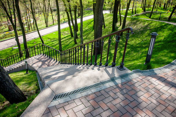 Staircase in landscape design, beautiful view of park. Beautiful park scene in public park with green grass field, stone paths and benches, green trees, landscape design - Фото, изображение