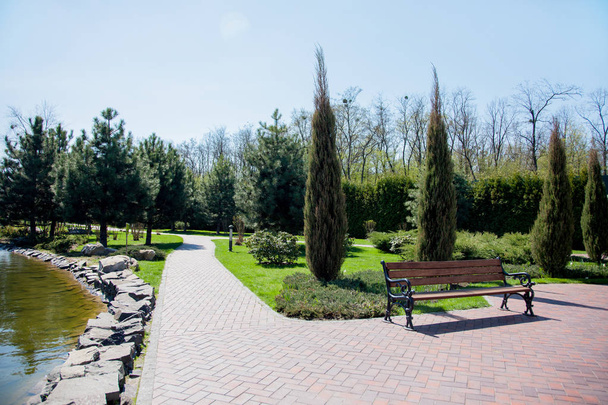 schöne Parkszene im öffentlichen Park mit grünen Rasenflächen, steinernen Wegen und Bänken, grünen Bäumen, Landschaftsgestaltung - Foto, Bild