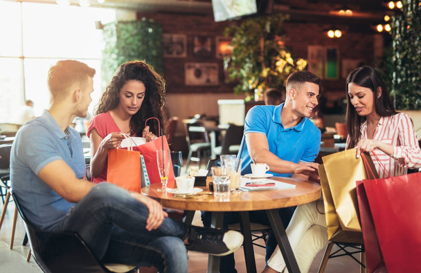 група щасливих молодих людей, що зустрічаються в кафе після покупки
 - Фото, зображення