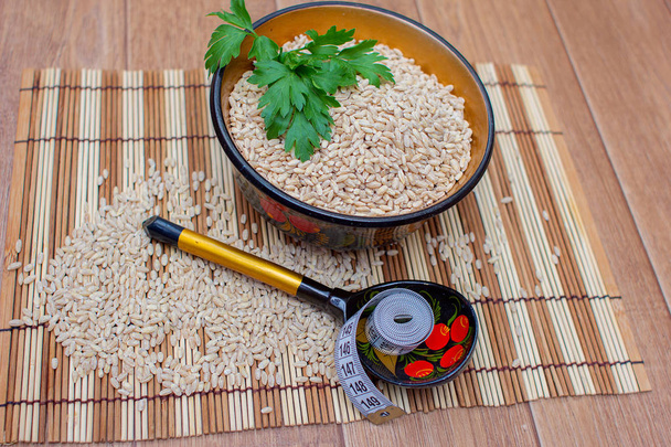 Pearl barley in a cup, nearby a spoon and a centimetric tape - Photo, Image