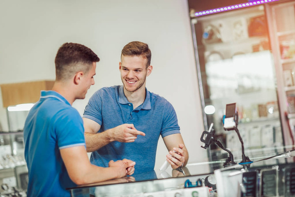 two smiling young men choosing smartphone in store  - Fotó, kép