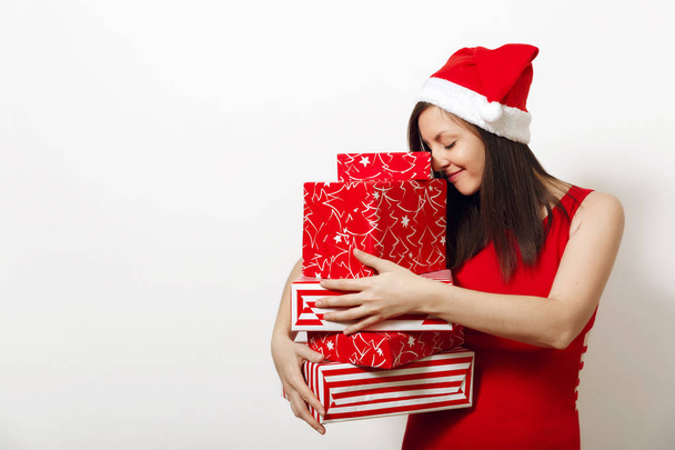 Bella caucasica giovane donna felice con affascinante sorriso vestito in abito rosso e cappello di Natale contenente scatole regalo su sfondo bianco. Santa ragazza con presente isolato. Concetto vacanza di Capodanno 2018
 - Foto, immagini