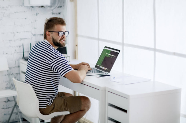 jovem sentado na mesa trabalhando no laptop no escritório moderno
 - Foto, Imagem