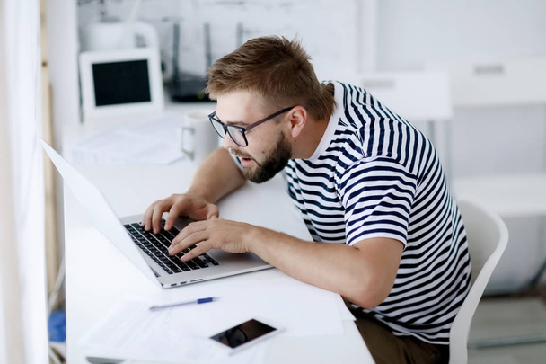 young handsome businessman typing on laptop sitting at desk in office - Fotografie, Obrázek