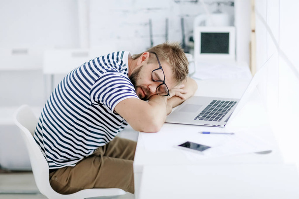 Tired man sitting at his working place and sleeping - Φωτογραφία, εικόνα
