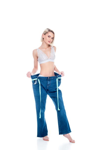 mooi slank meisje in oude jeans met meetlint, geïsoleerd op wit - Foto, afbeelding