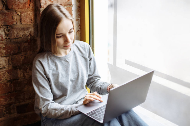 Young beautiful woman is using laptop. - Fotografie, Obrázek