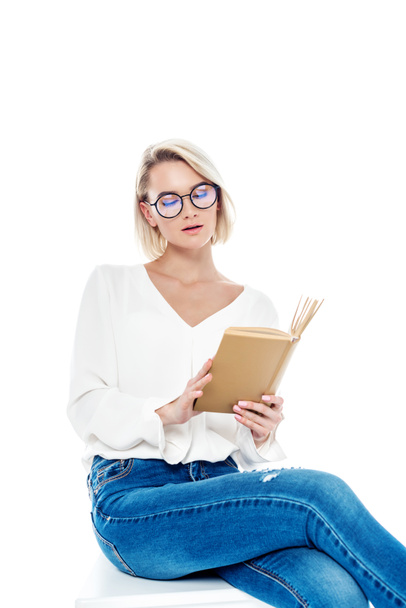attractive blonde girl in glasses reading book, isolated on white - Фото, изображение