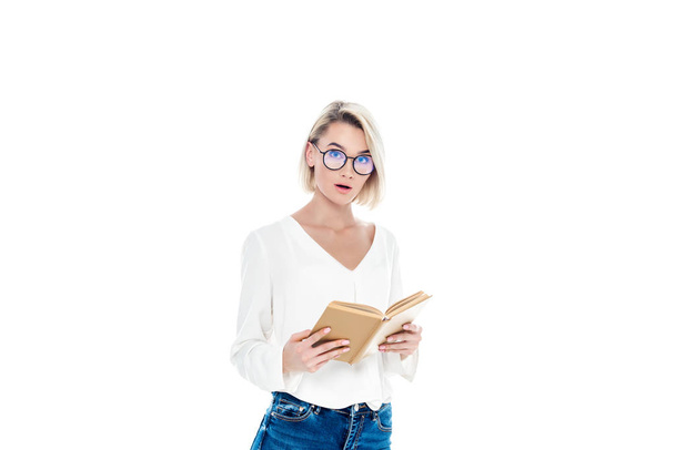 beautiful surprised student in eyeglasses reading book, isolated on white - Φωτογραφία, εικόνα
