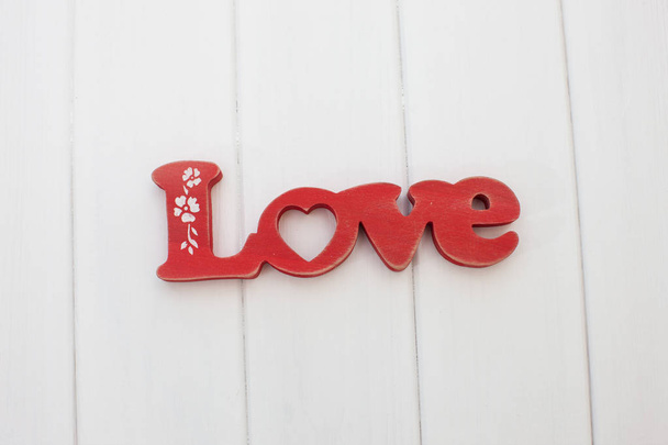 Red wooden letters love on white wooden planks background - Fotó, kép