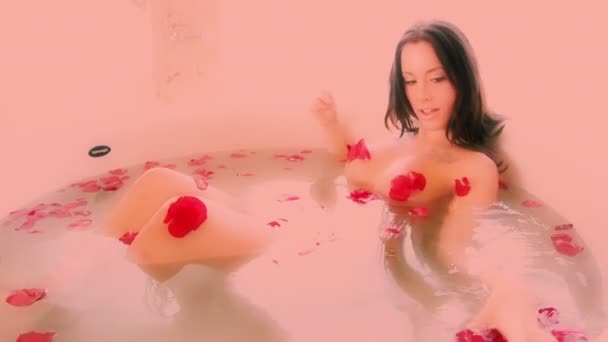 Seksikäs kaunis nainen liottaa ylellisessä kylvyssä peitetty ruusun terälehtiä
 - Materiaali, video