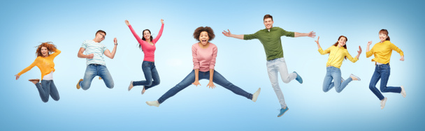happy people or friends jumping in air over blue - Photo, Image