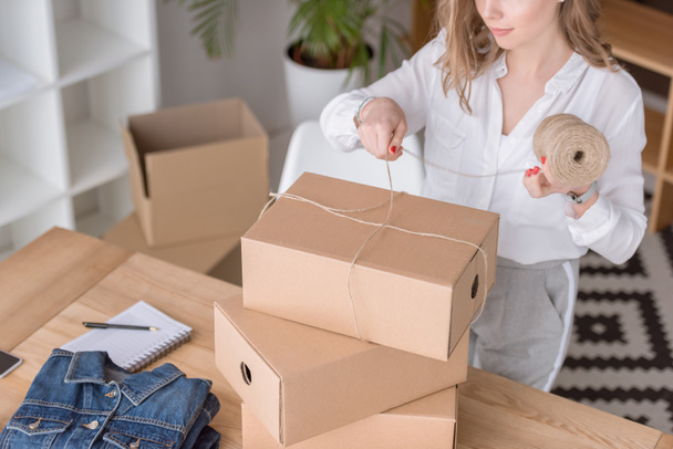 partial view of entrepreneur packing customers purchase in cardboard boxes at home office - Photo, Image