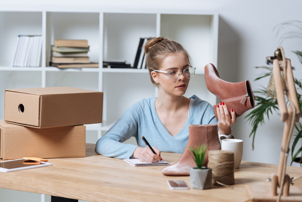 retrato de empreendedor focado com par de sapatos e notebook trabalhando à mesa no escritório em casa
 - Foto, Imagem