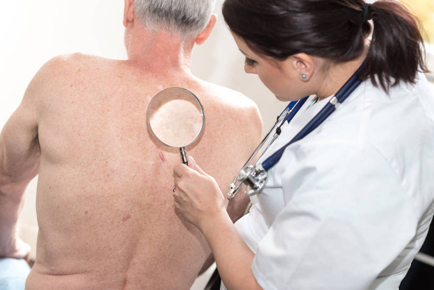 Женщина-врач проверяет кожу пожилого пациента
 - Фото, изображение