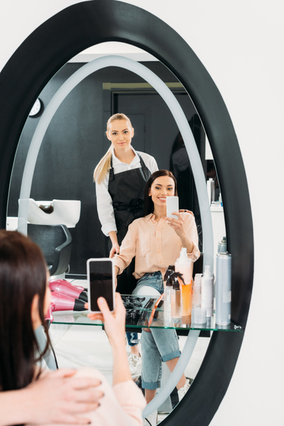 femme heureuse prenant selfie de nouvelle coiffure en miroir au salon
 - Photo, image