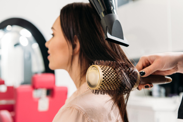 cropped image of hairdresser styling hair with round hair brush - Photo, Image