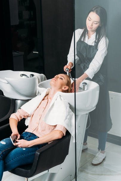 salon fryzjerski w fartuch, mycie włosów klienta  - Zdjęcie, obraz