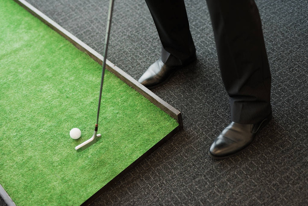Close up. A man in a business suit plays golf in the office - Foto, afbeelding