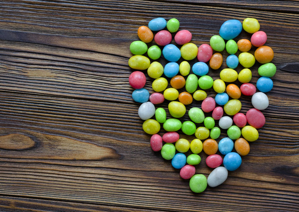 corazón de caramelos multicolores sobre fondo de madera
 - Foto, imagen