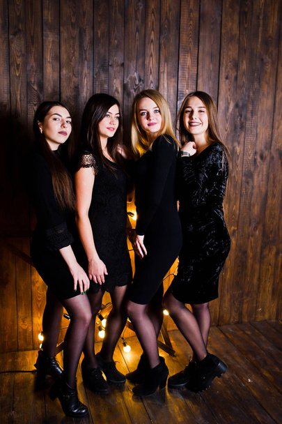 Four cute friends girls wear black dresses against large light c - Foto, Imagen