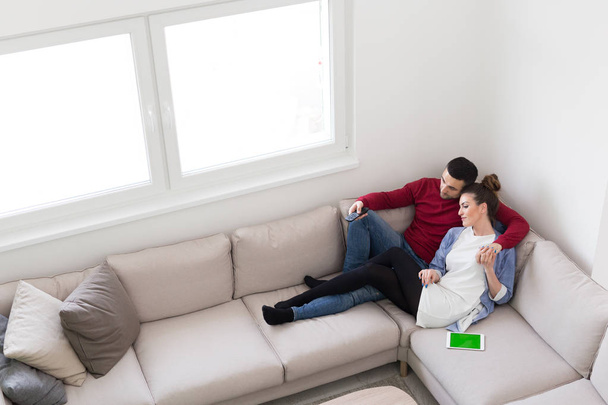 Молодая пара на диване смотрит телевизор
 - Фото, изображение