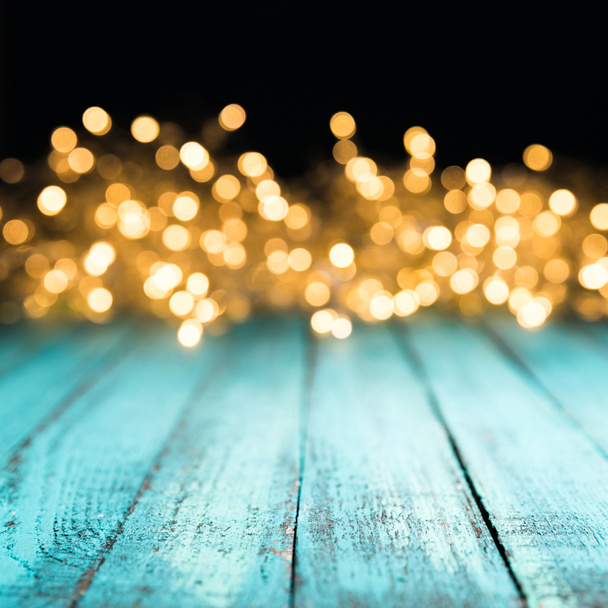 decorative bokeh lights on blue wooden surface, christmas background - Photo, Image