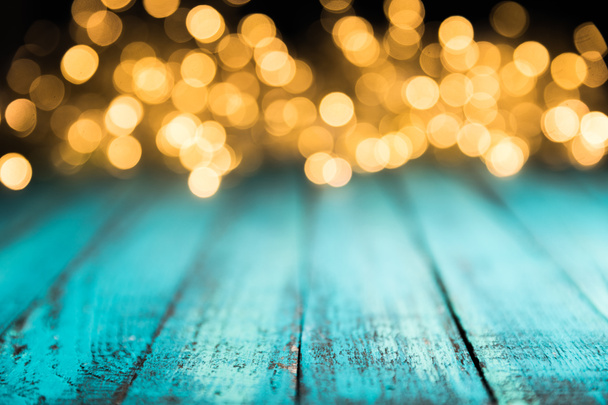 festive bokeh lights on blue wooden surface, christmas background - Photo, Image