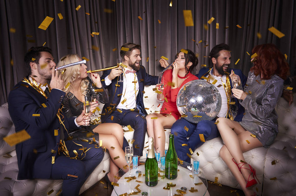 Grupo de amigos celebrando año nuevo entre confeti caída
  - Foto, Imagen
