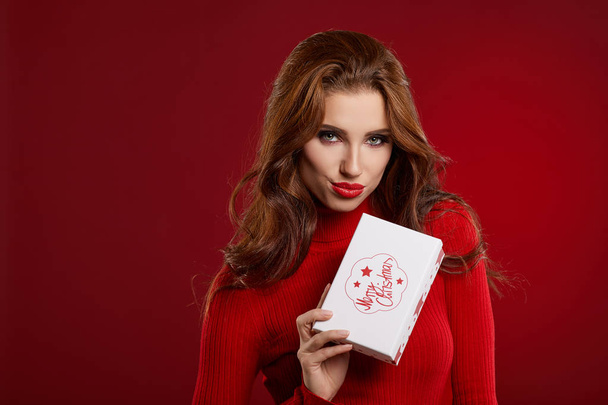 Frau mit Weihnachtsschachtel Geschenk posiert auf rotem Hintergrund  - Foto, Bild