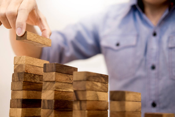 Hombre de negocios a mano poner bloques de madera que arreglan el apilamiento para el desarrollo
 - Foto, Imagen