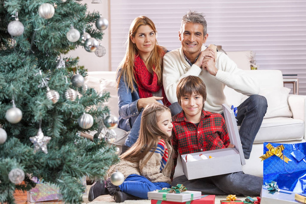 Ευτυχισμένη οικογένεια κάτω από το χριστουγεννιάτικο δέντρο στο σπίτι - Φωτογραφία, εικόνα