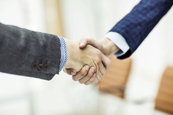 concept of a reliable partnership: a handshake of business partners on blurred light background - 写真・画像
