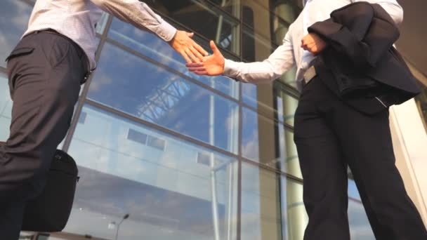 Two businessmen meeting near office building and greeting each other. Business handshake outdoor in urban environment. Shaking of male arms outside. Colleagues shake hands. Close up Slow motion - Footage, Video