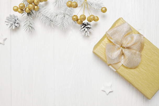Weihnachtsgeschenk-Attrappe mit goldener Schleife und Baumkegel, flach auf weißem Holzgrund, mit Platz für Ihren Text - Foto, Bild