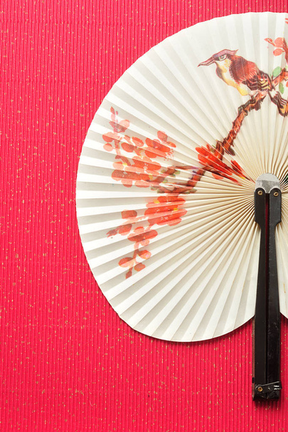 A chinese hand fan isolated on a red background - Photo, Image