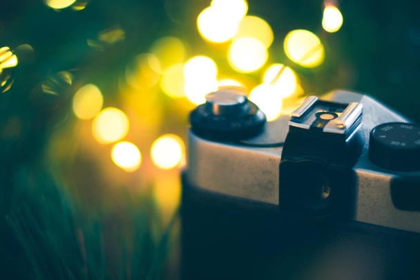 The old camera on a wooden background with Christmas tree branches and lights. - Foto, Bild