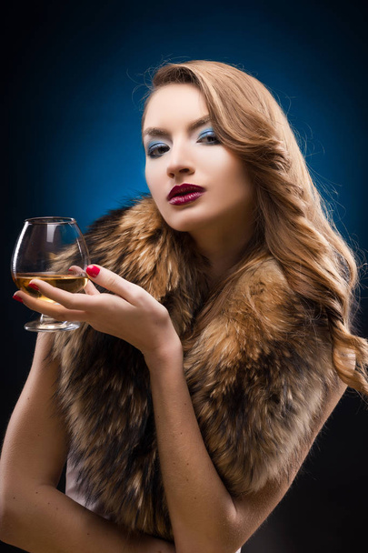 Beautiful girl in a fur raccoon collar holds in hands a glass of - Foto, imagen